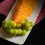 green grapes and cantaloupe on a white serving platter.