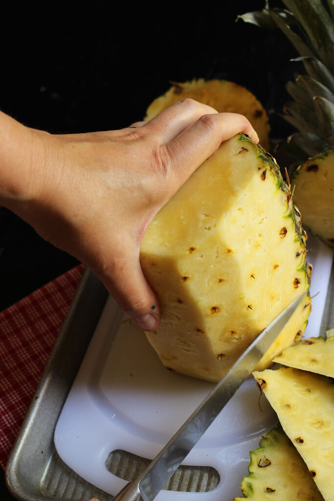 cutting all the rind off the pineapple.