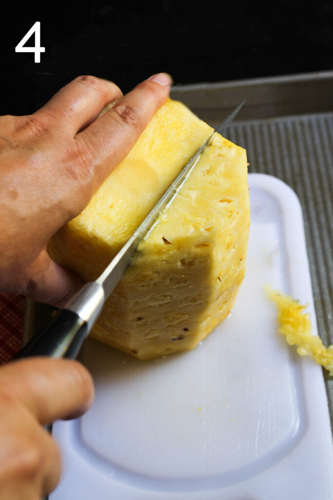 cutting the knife to the right of the core, through the whole pineapple without rind.