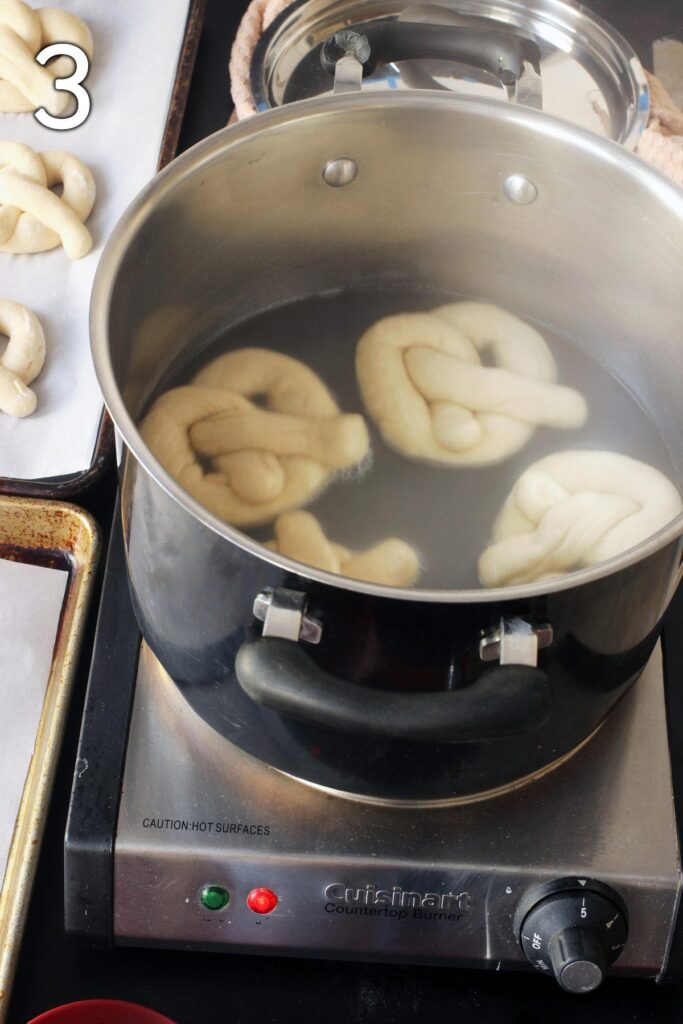 four pretzels boiling in the pot of hot water.