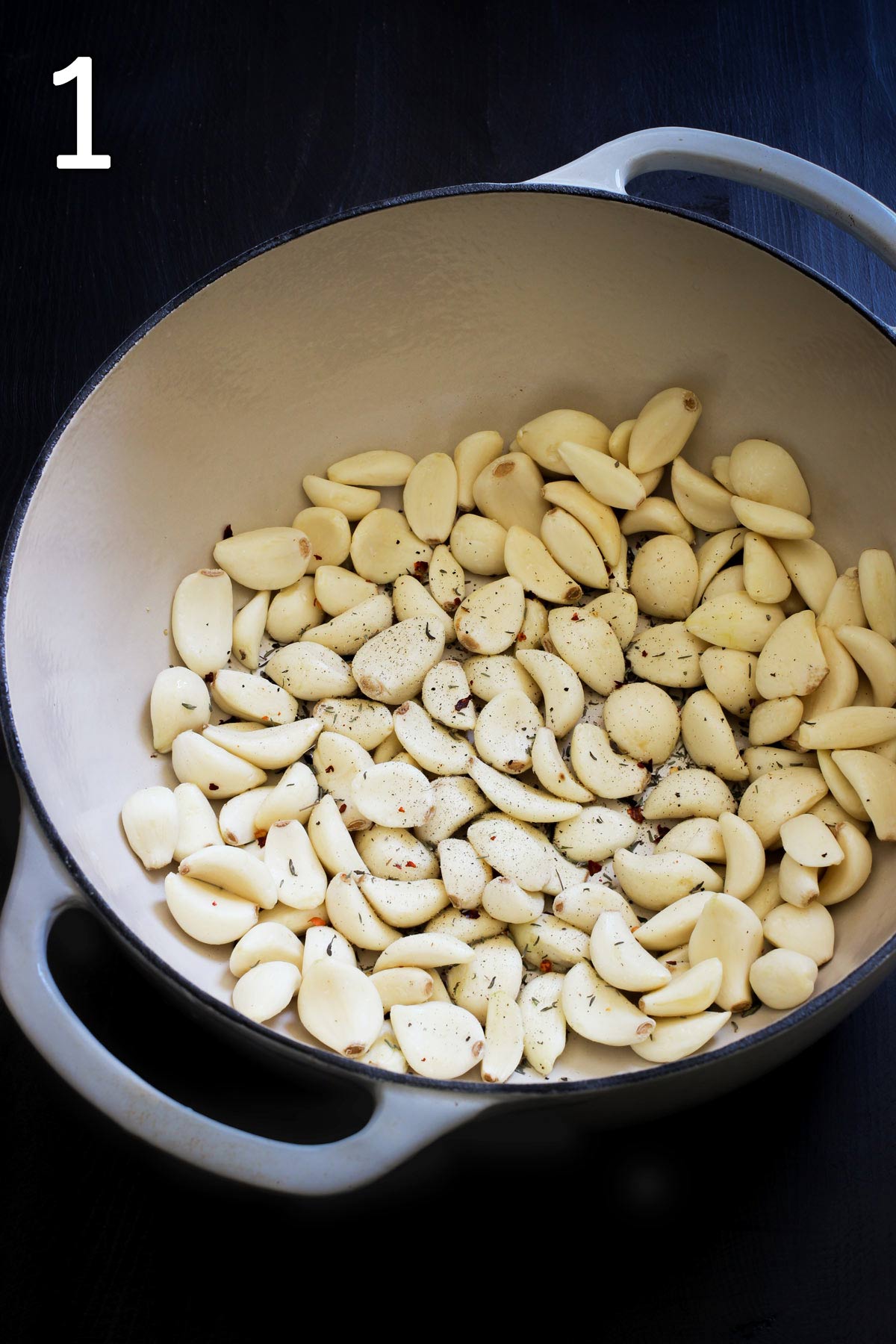 peeled garlic cloves in a dutch oven with spices.