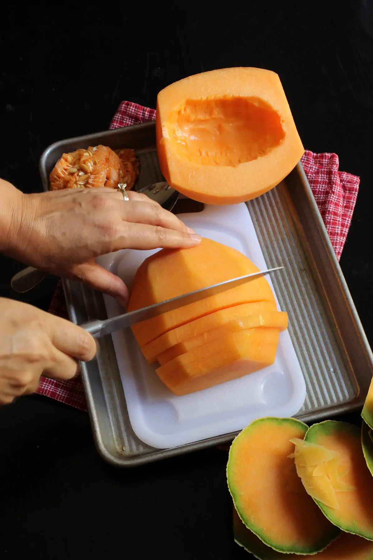 cutting cantaloupe half into slices on cutting board.