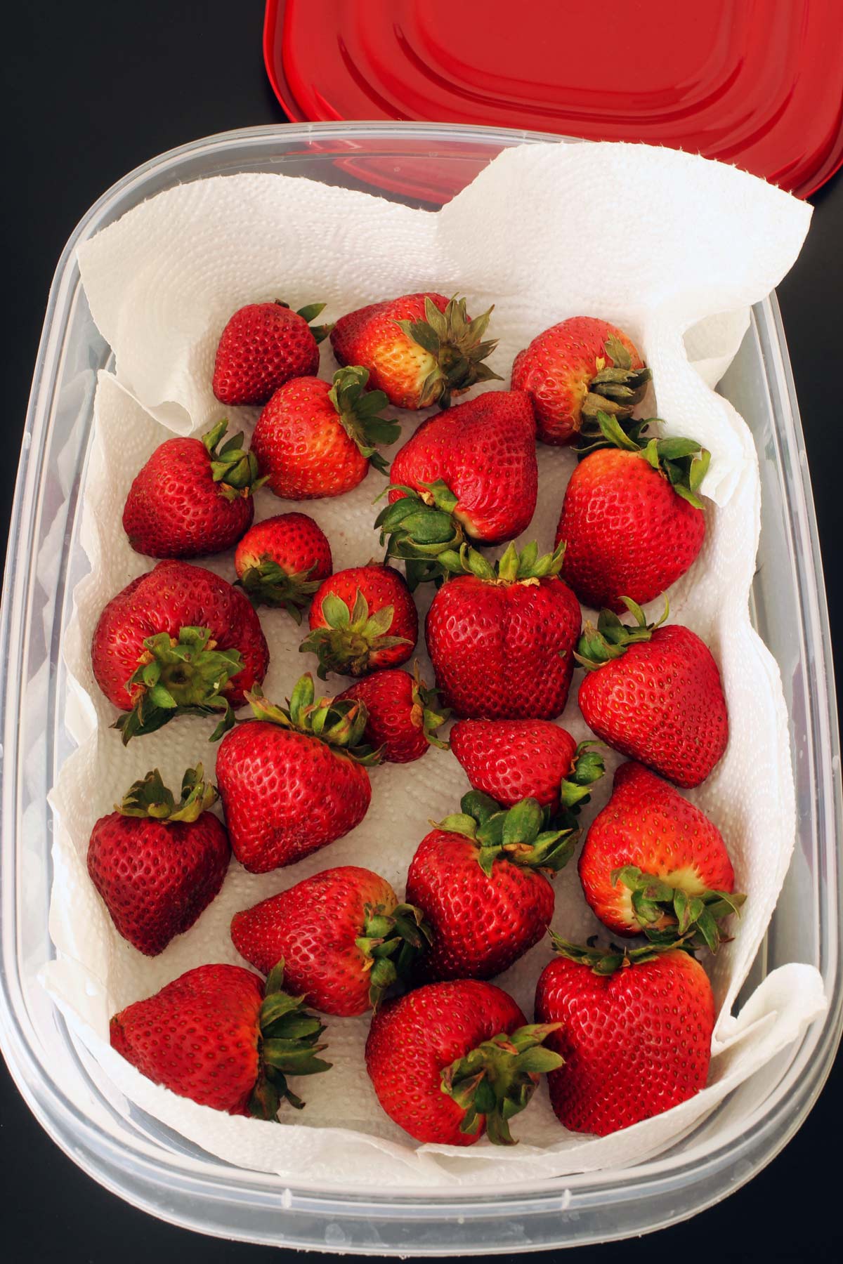 strawberries in paper towel lined plastic container.
