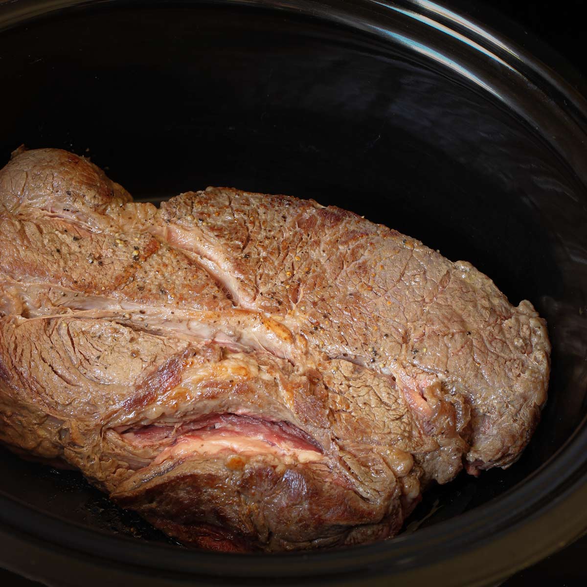 seared chuck roast in the crock of the slow cooker.