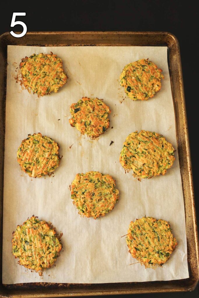 eight baked zucchini fritters on lined sheet pan.