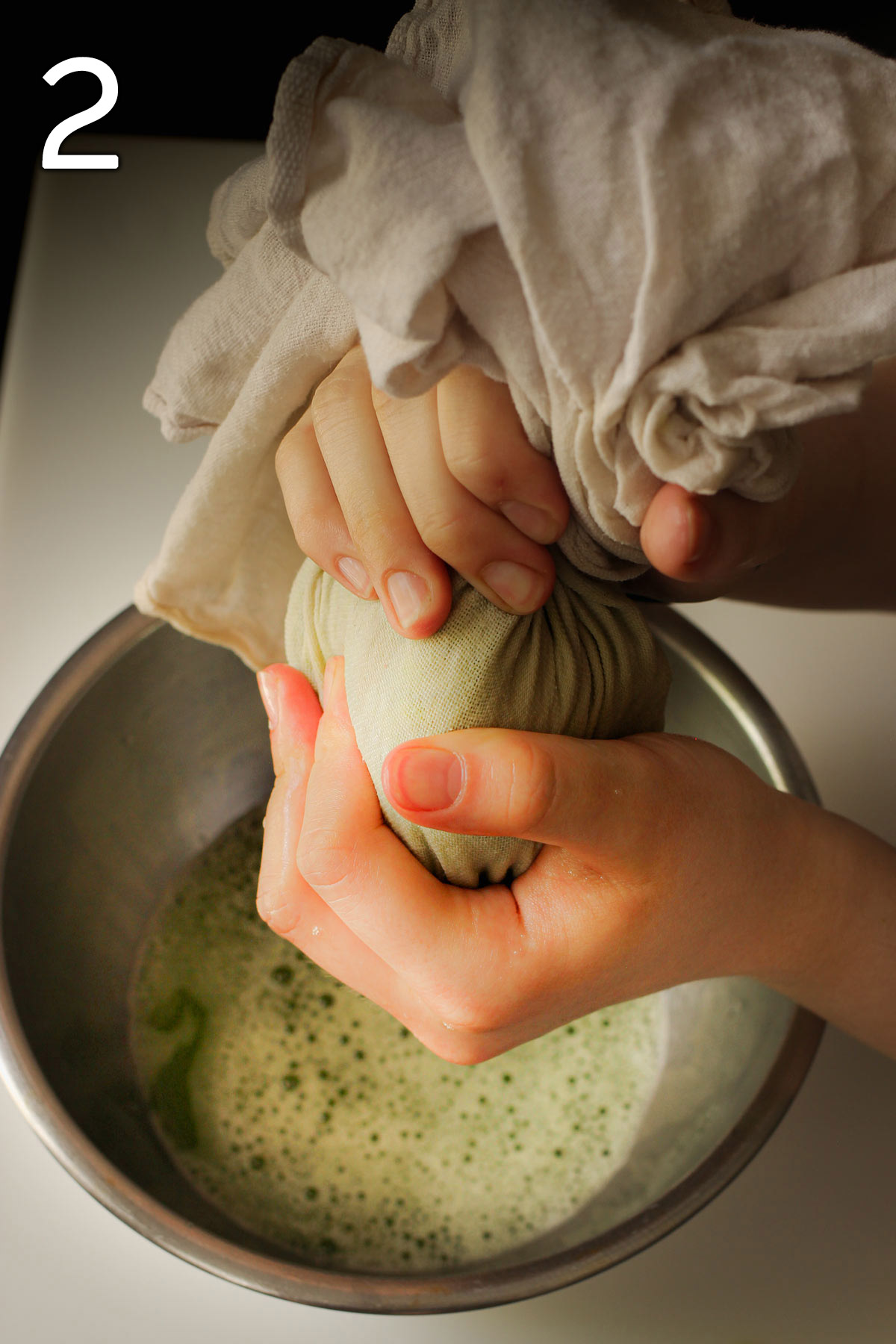 squeezing zucchini-filled tea towel over a bowl filled with zucchini liquid.