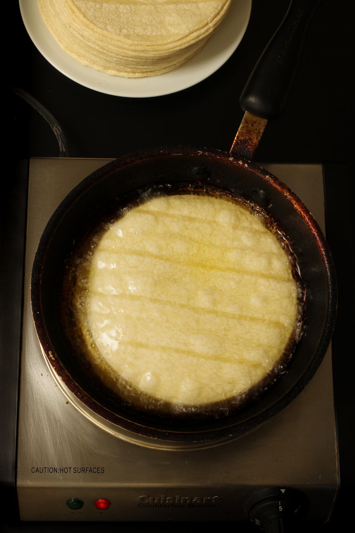 frying corn tortilla in hot oil.