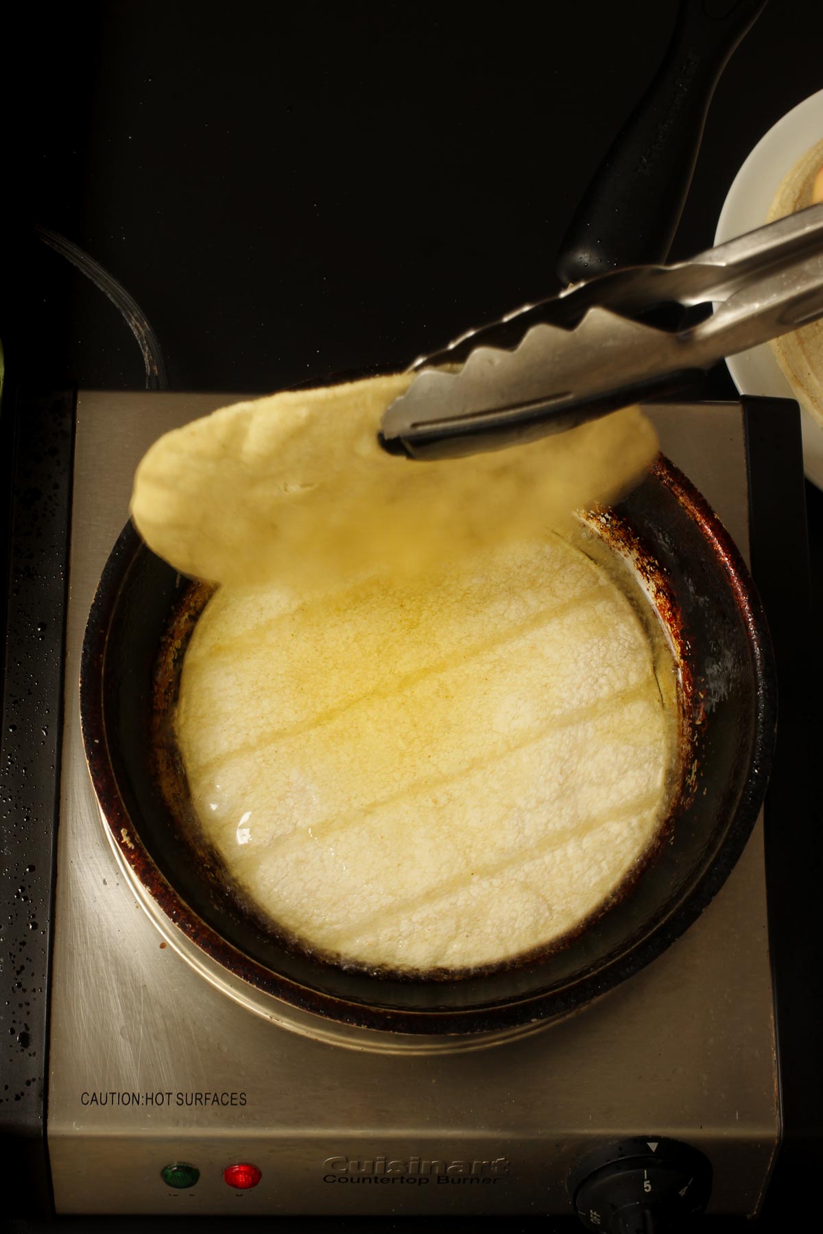letting one tortilla drip oil back into the pan while the next one is frying.