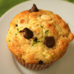 zucchini muffin with dark and white chocolate chips poking out the top.