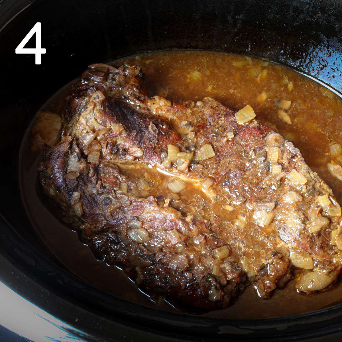 cooked and browned chuck roast in slow cooker with onions and juices.