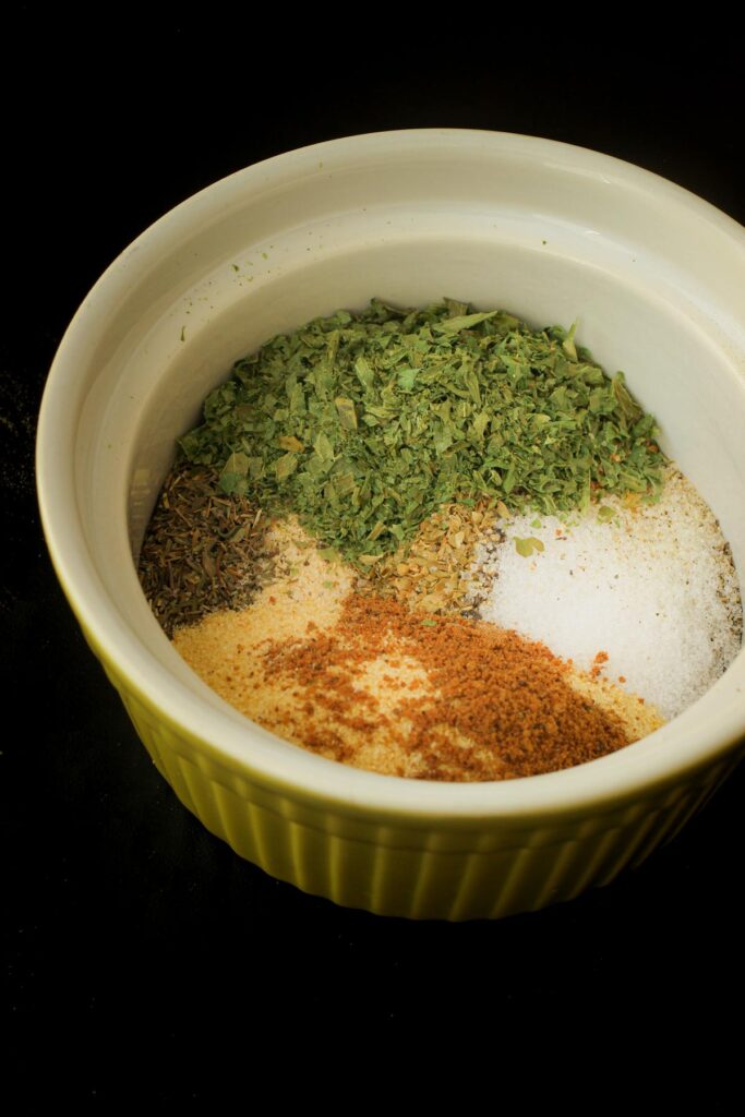 ingredients for greek spice blend assembled in small green bowl.