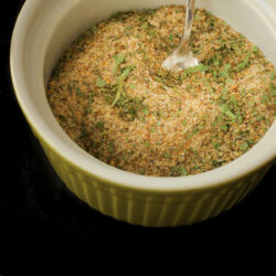 green bowl with greek spice blend and small spoon.