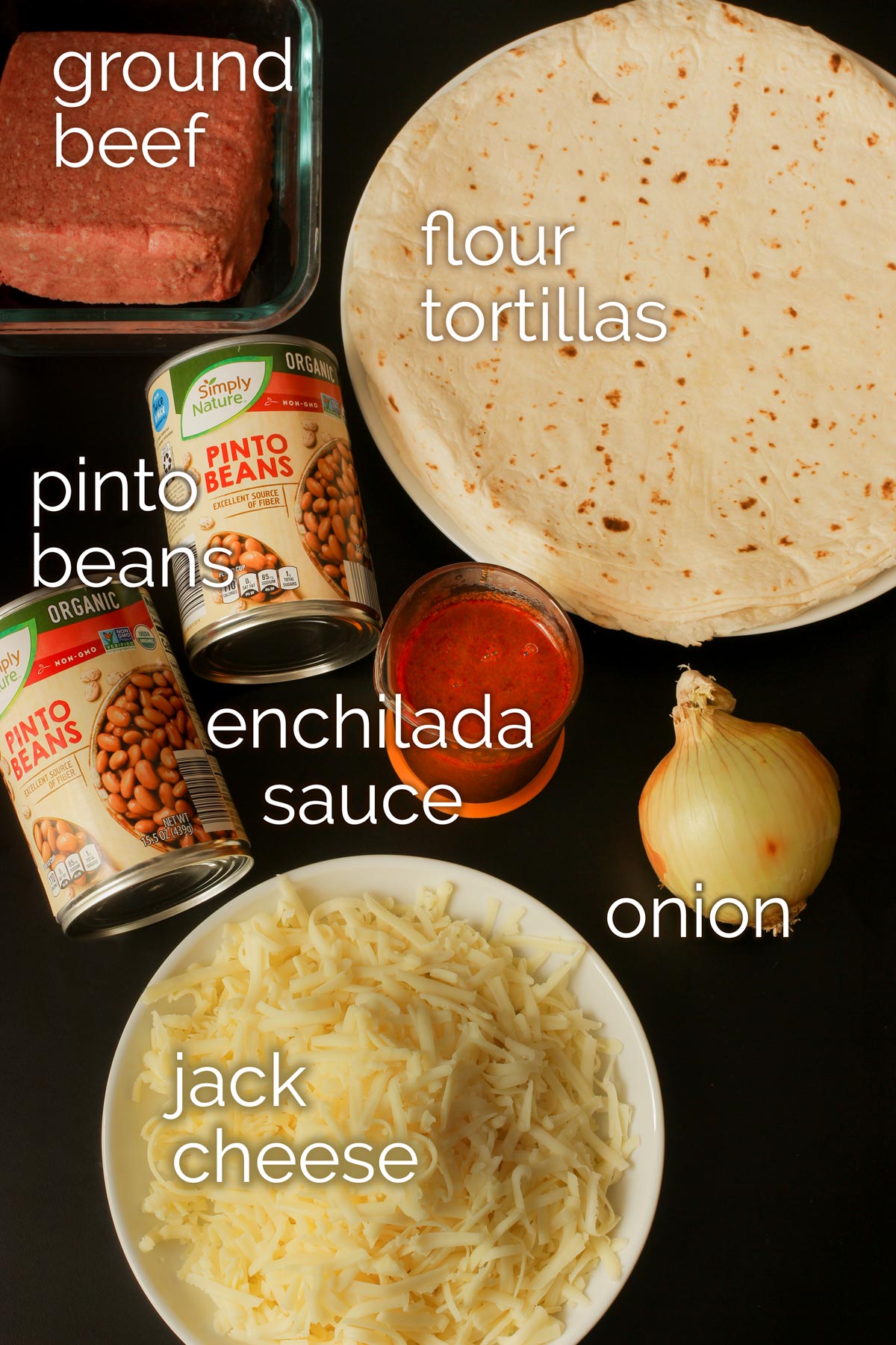 ingredients for bean and beef burritos laid out on black countertop.