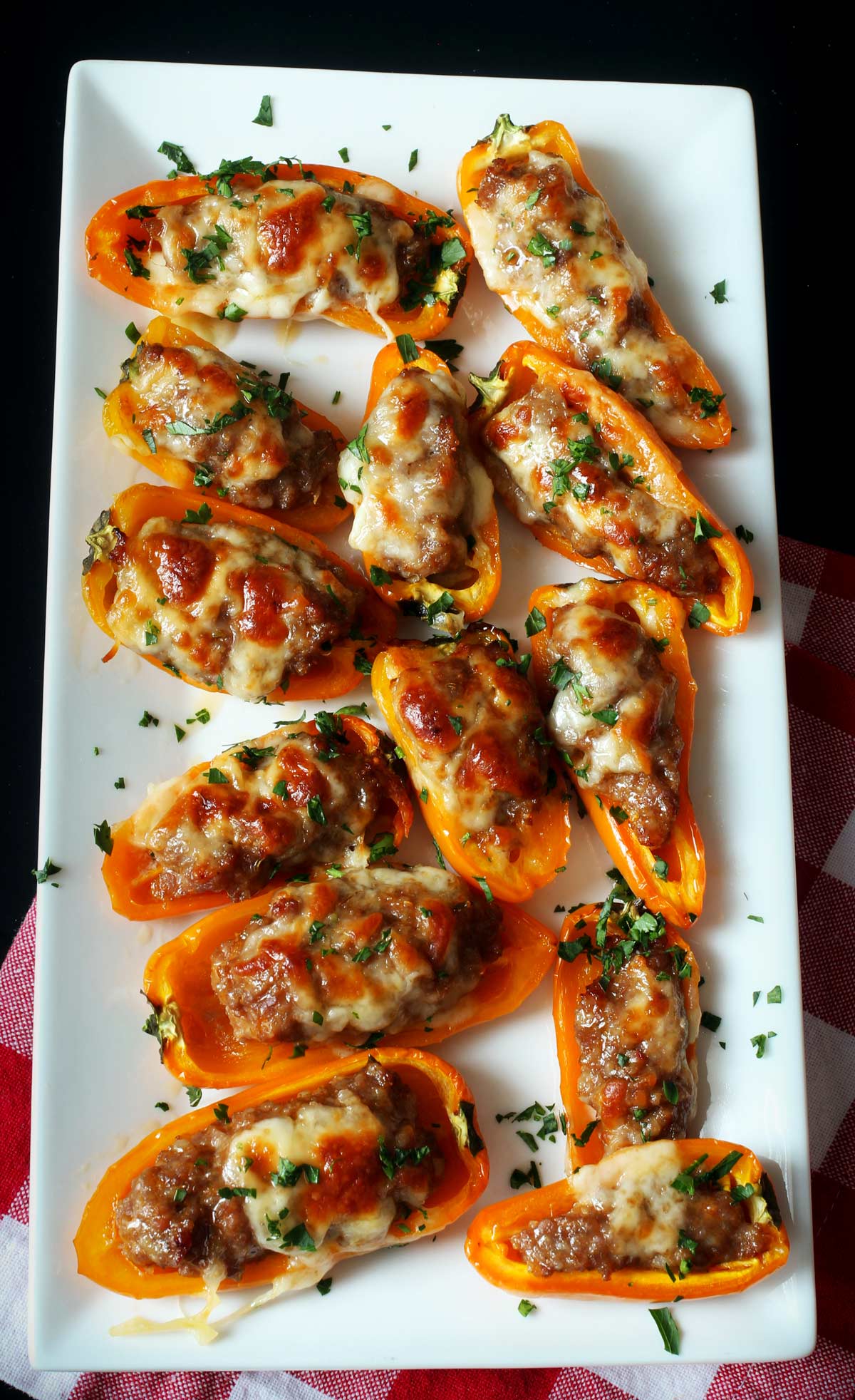 platter of stuffed mini peppers loaded with sausage and topped with melted cheese.