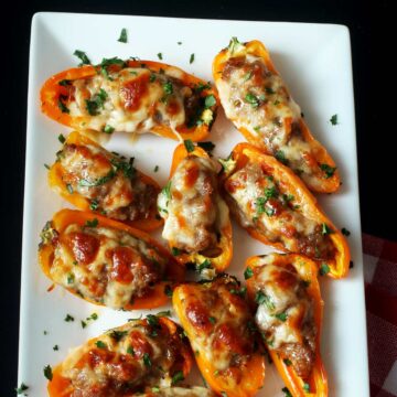 mini peppers stuffed with sausage and cheese on white platter.