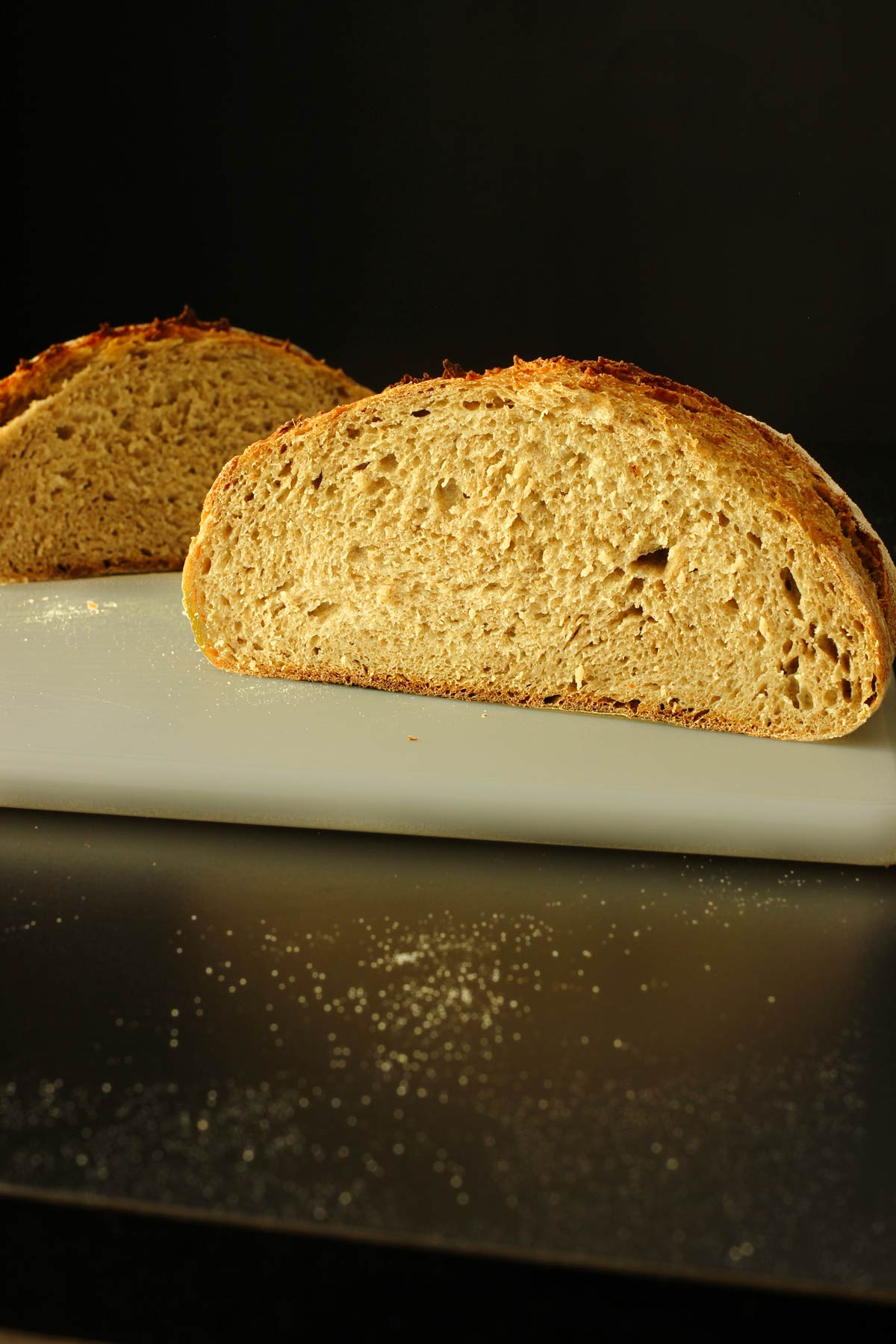 loaf of sourdough rye on the cutting board cut in half.