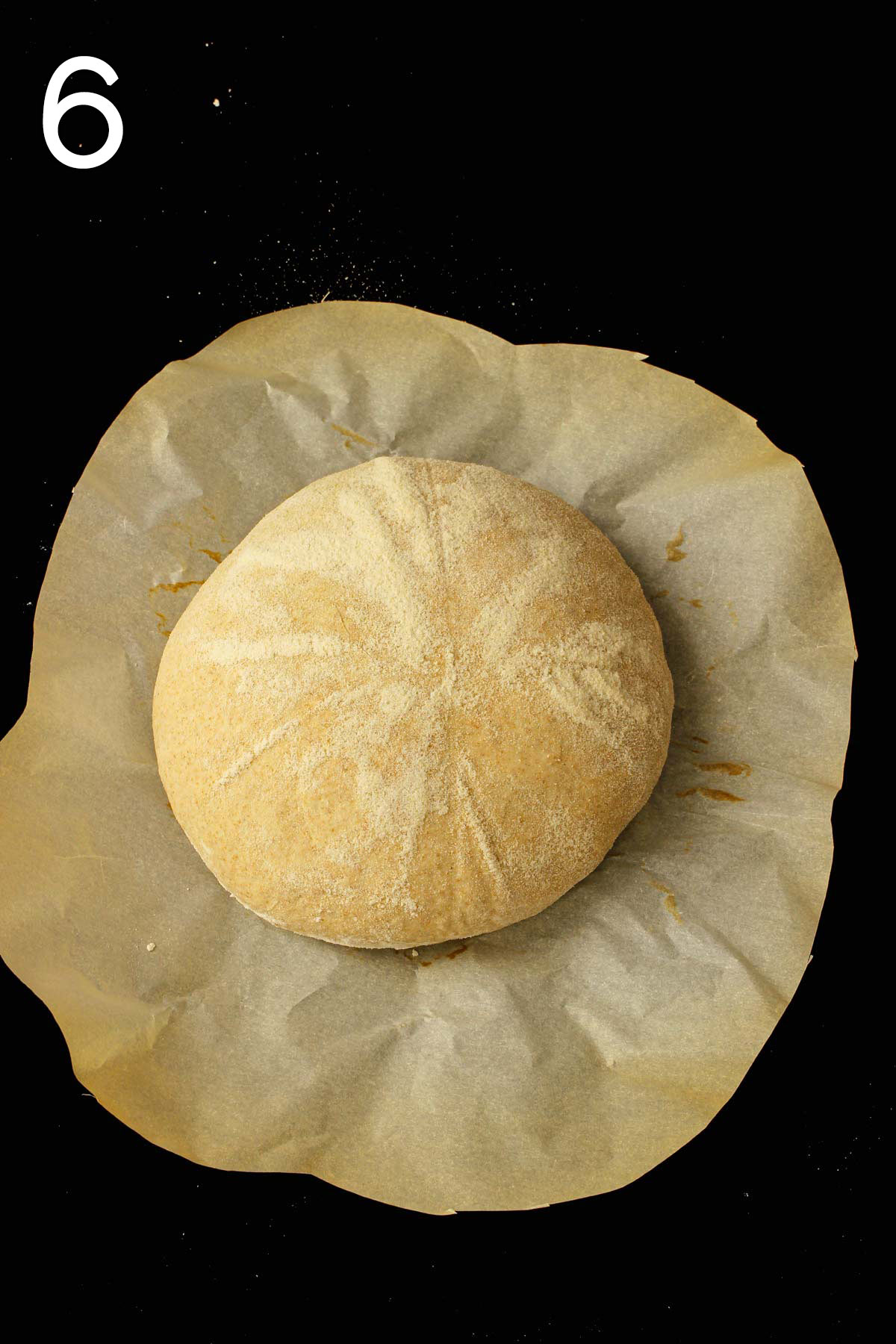 smooth risen boule on parchment paper round ready for slashing.