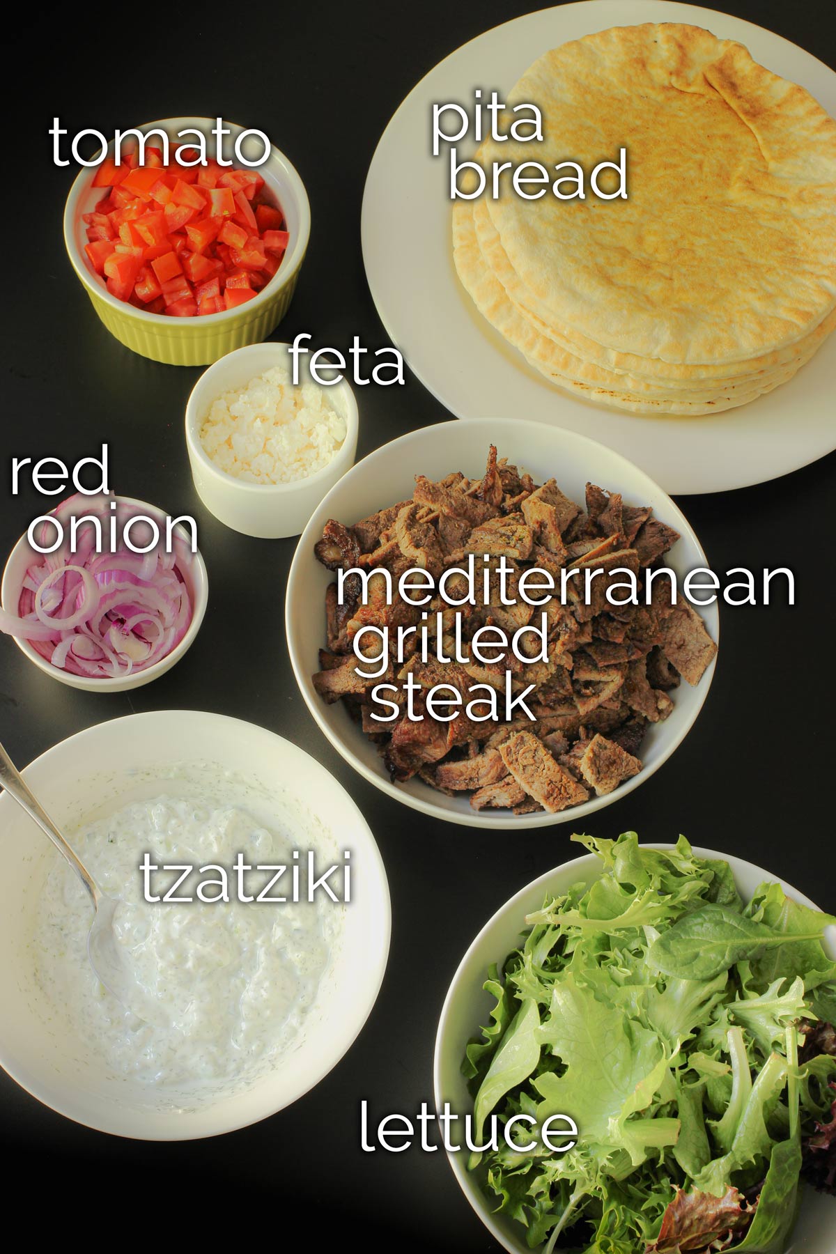 ingredients for greek pita sandwiches laid out on the table.