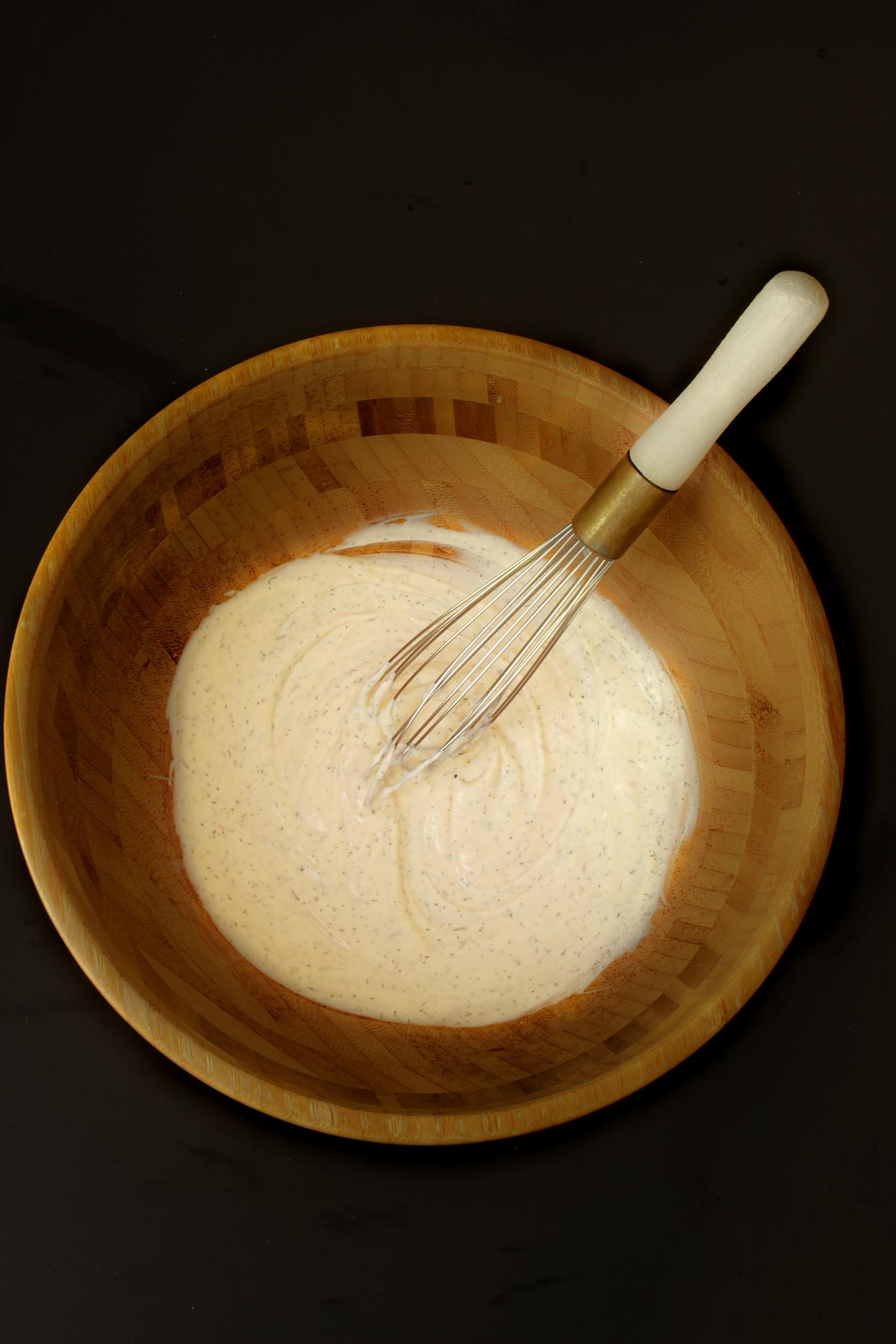 the dressing ingredients whisked together in a wooden salad bowl.
