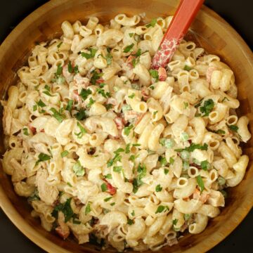 tuna macaroni salad in large wooden bowl with a red spoon.