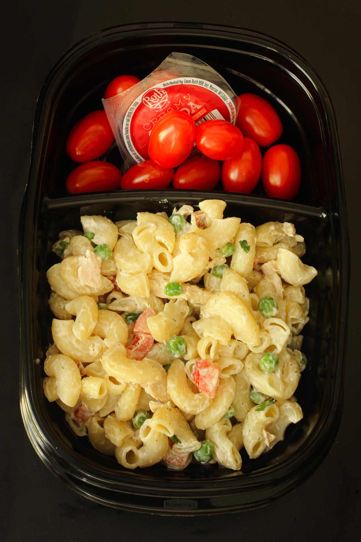 tuna pasta salad in sectioned black meal prep dish with grape tomatoes and snacking cheese in other section.