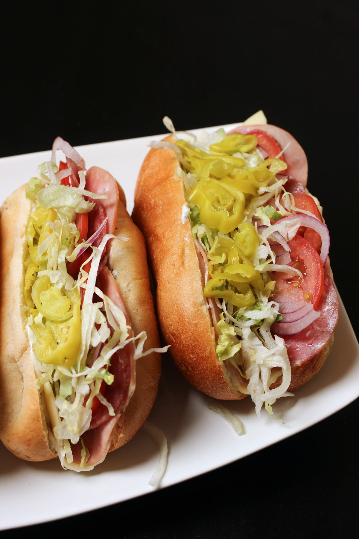 two Italian sub sandwiches on a white platter.