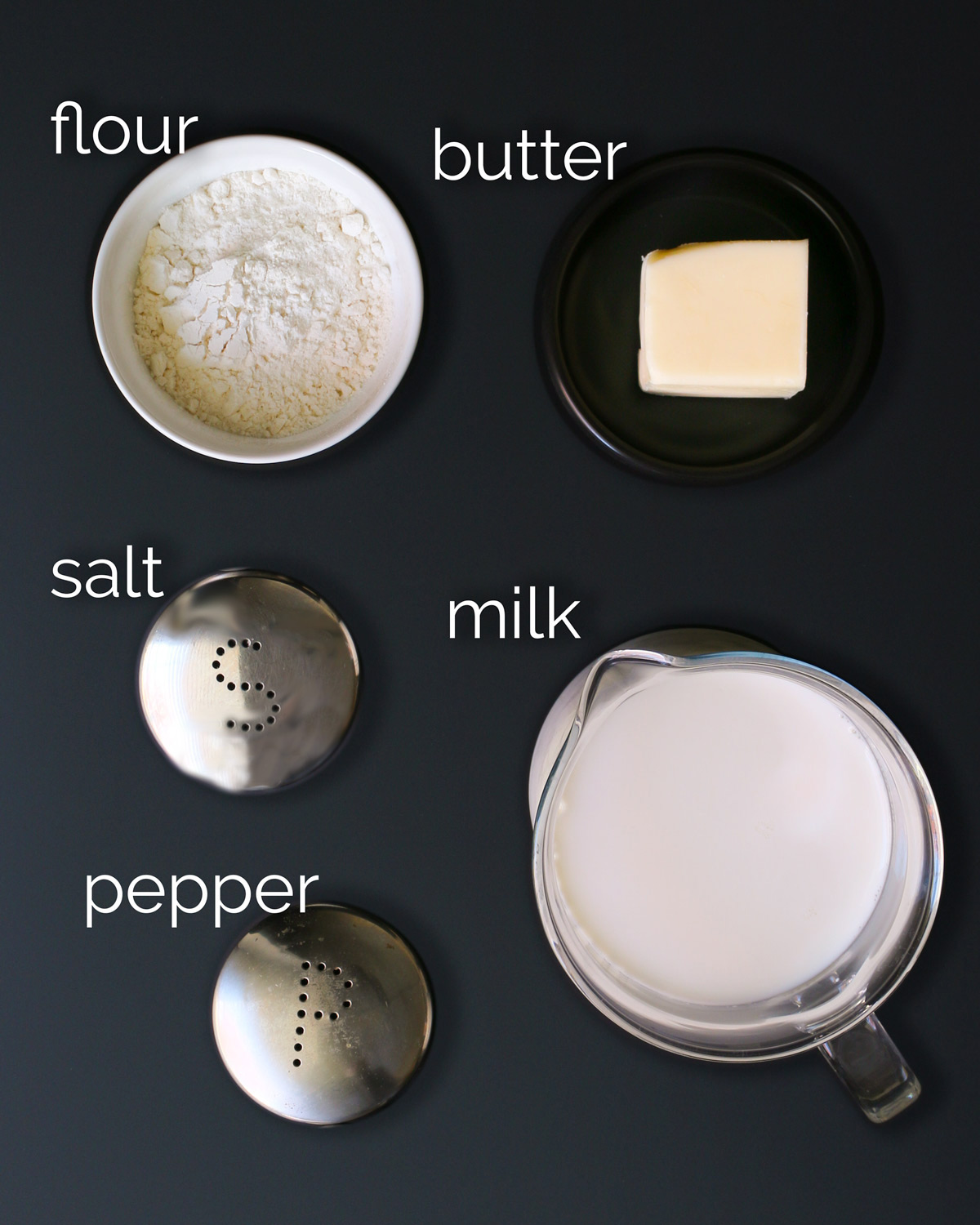 ingredients for white sauce laid out on black counter.