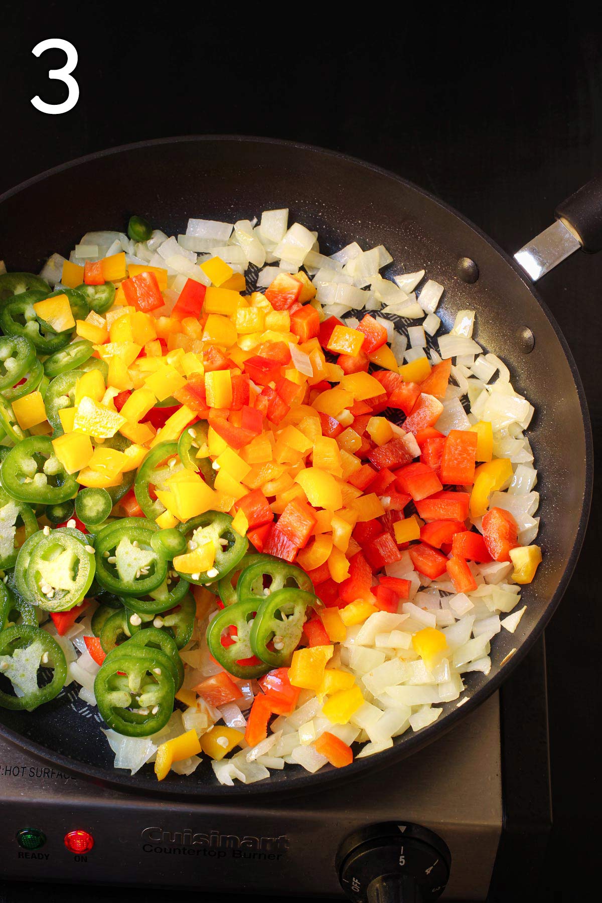 adding the peppers and chiles to the onions in the skillet.