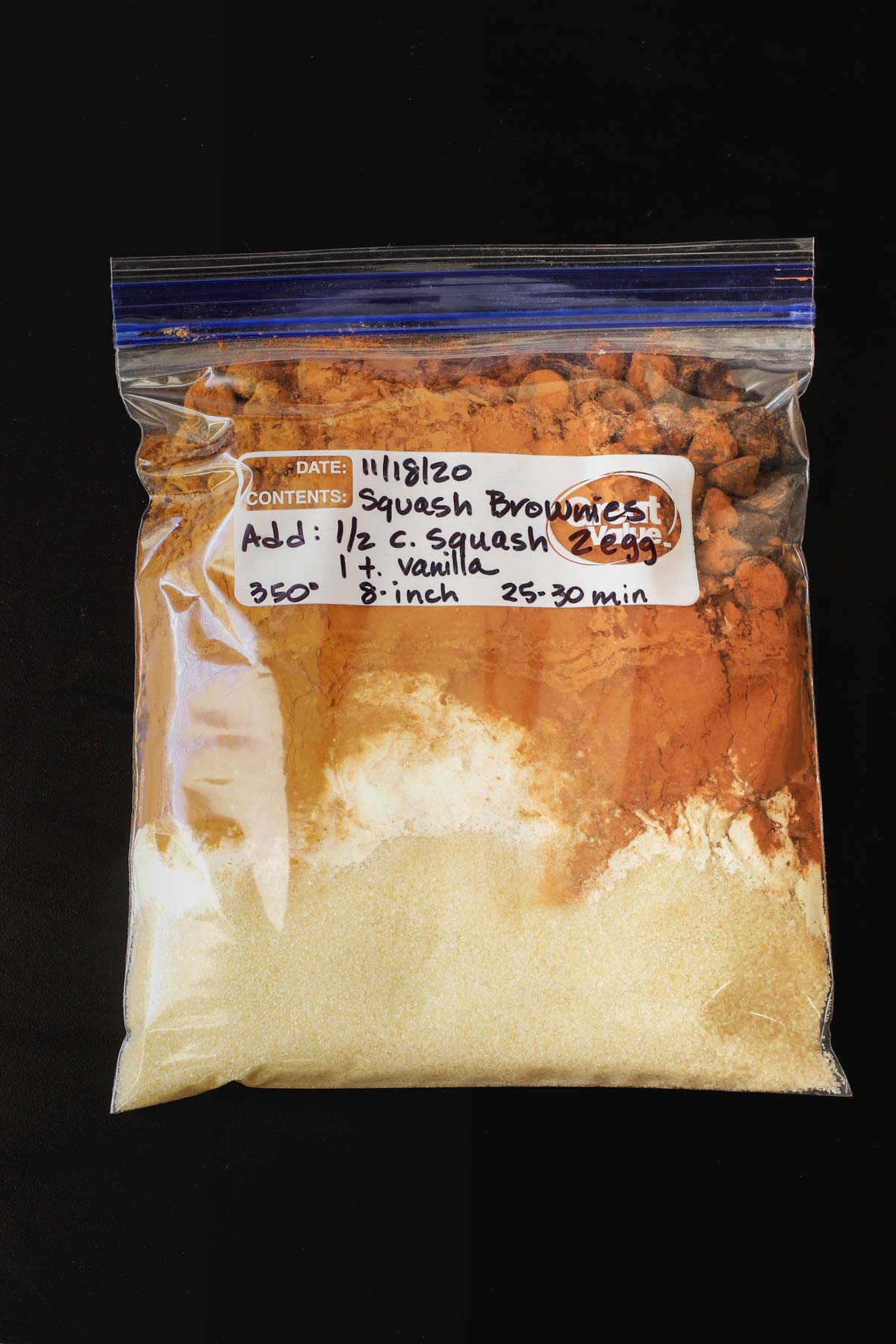 a brownie mix in a labeled ziptop freezer bag on a black tabletop.