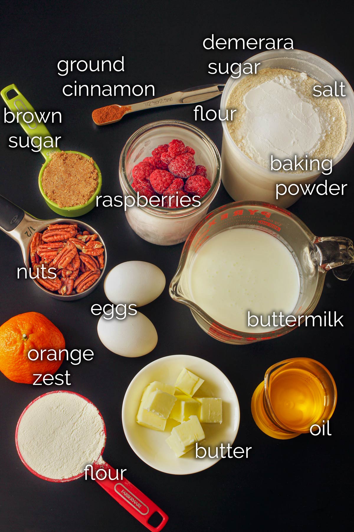 ingredients for raspberry muffins on a black tabletop.