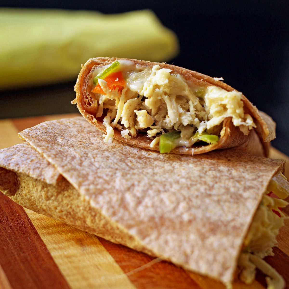 chicken fajita burrito cut in half with one half resting on the other, showing the cut side.