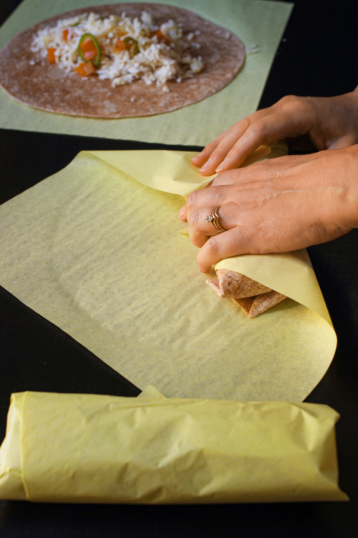 hands wrapping the rolled burrito in a deli wrap.