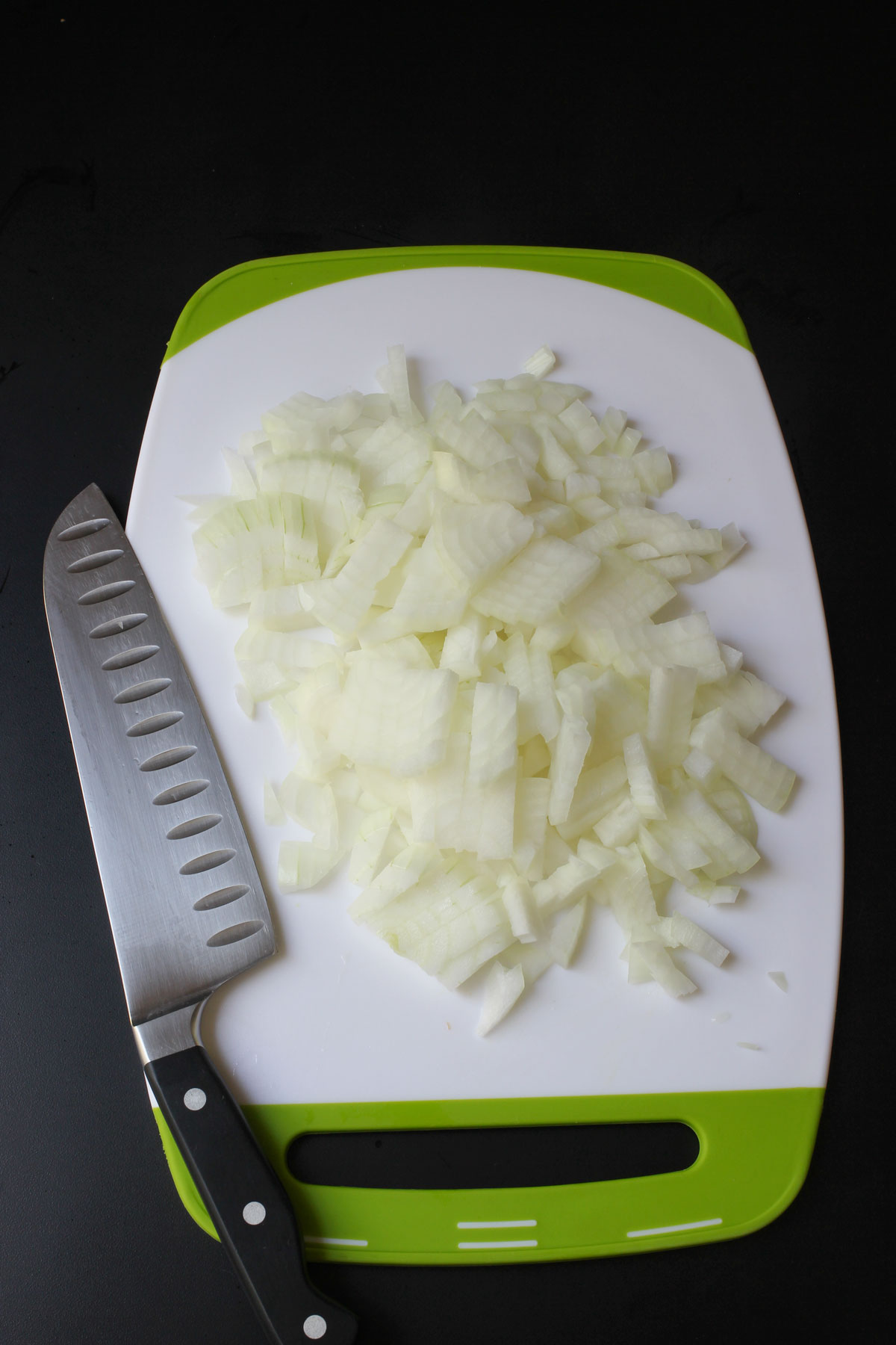 chopped onions on cutting board next to knife.