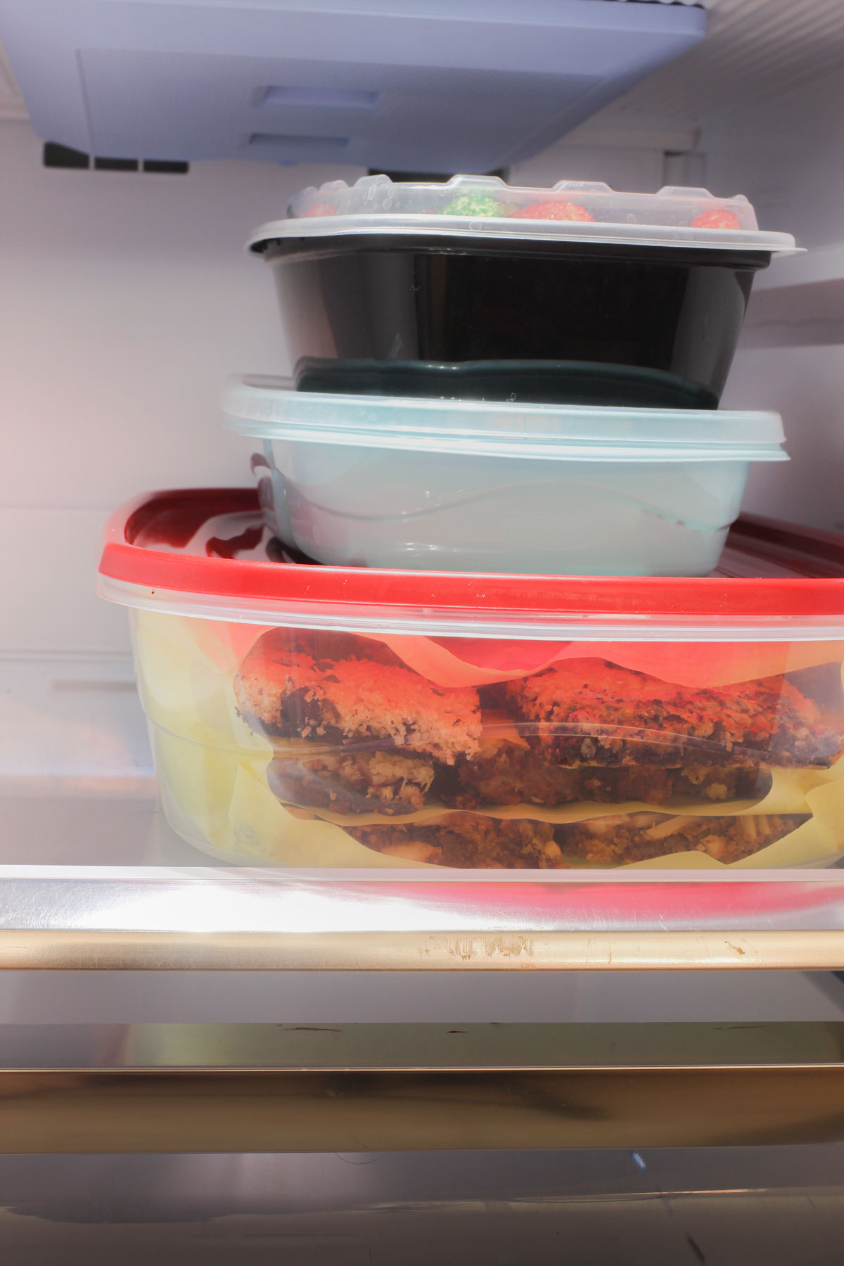 cookies in plastic containers stored on a freezer shelf.