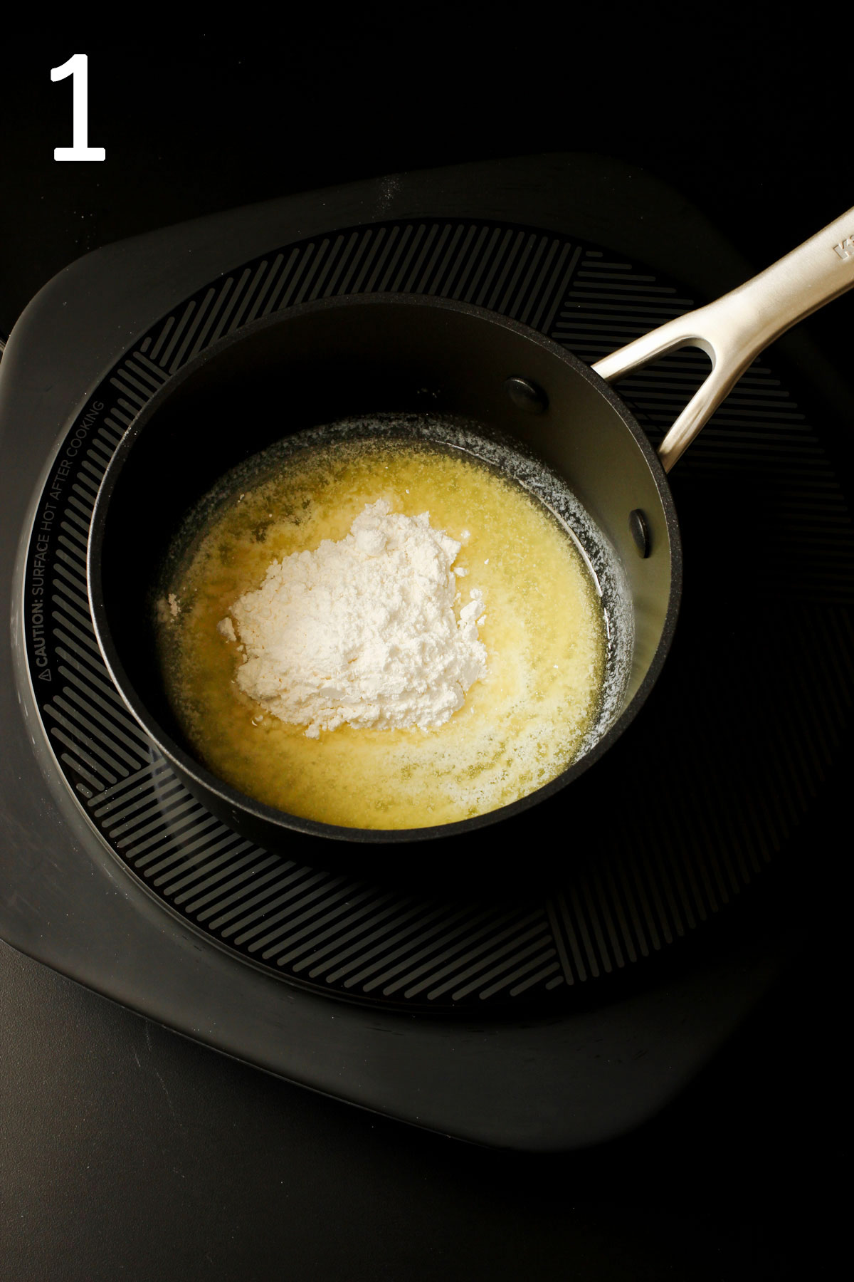 adding flour to butter to create a roux into a sauce pan.