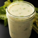 close-up of cream of celery soup in a jar with celery leaves behind.