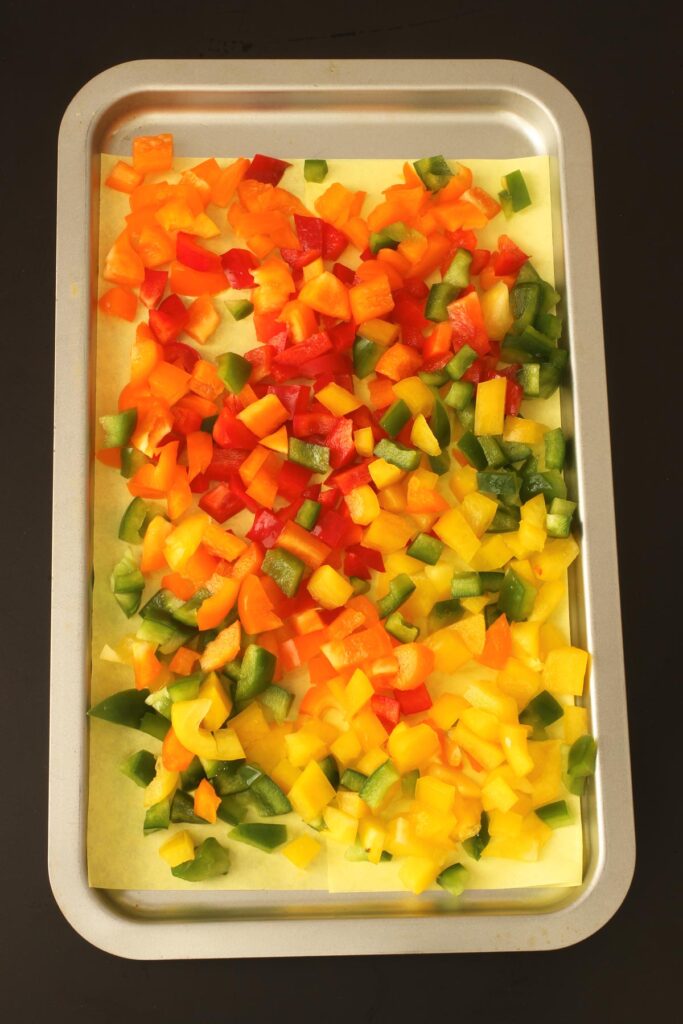 chopped colored bell peppers on lined tray for freezing.