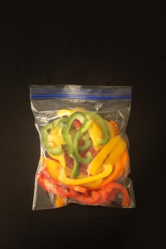 sliced colored bell peppers in ziptop freezer bag.