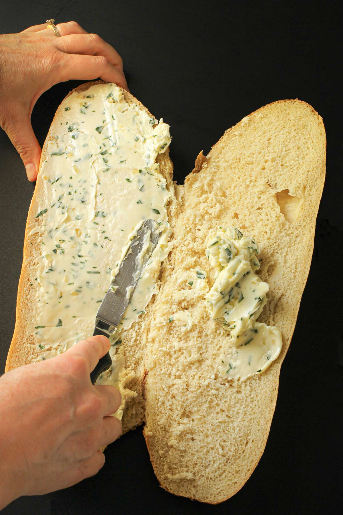 spreading the garlic butter evenly over the cut-sides of the bread.