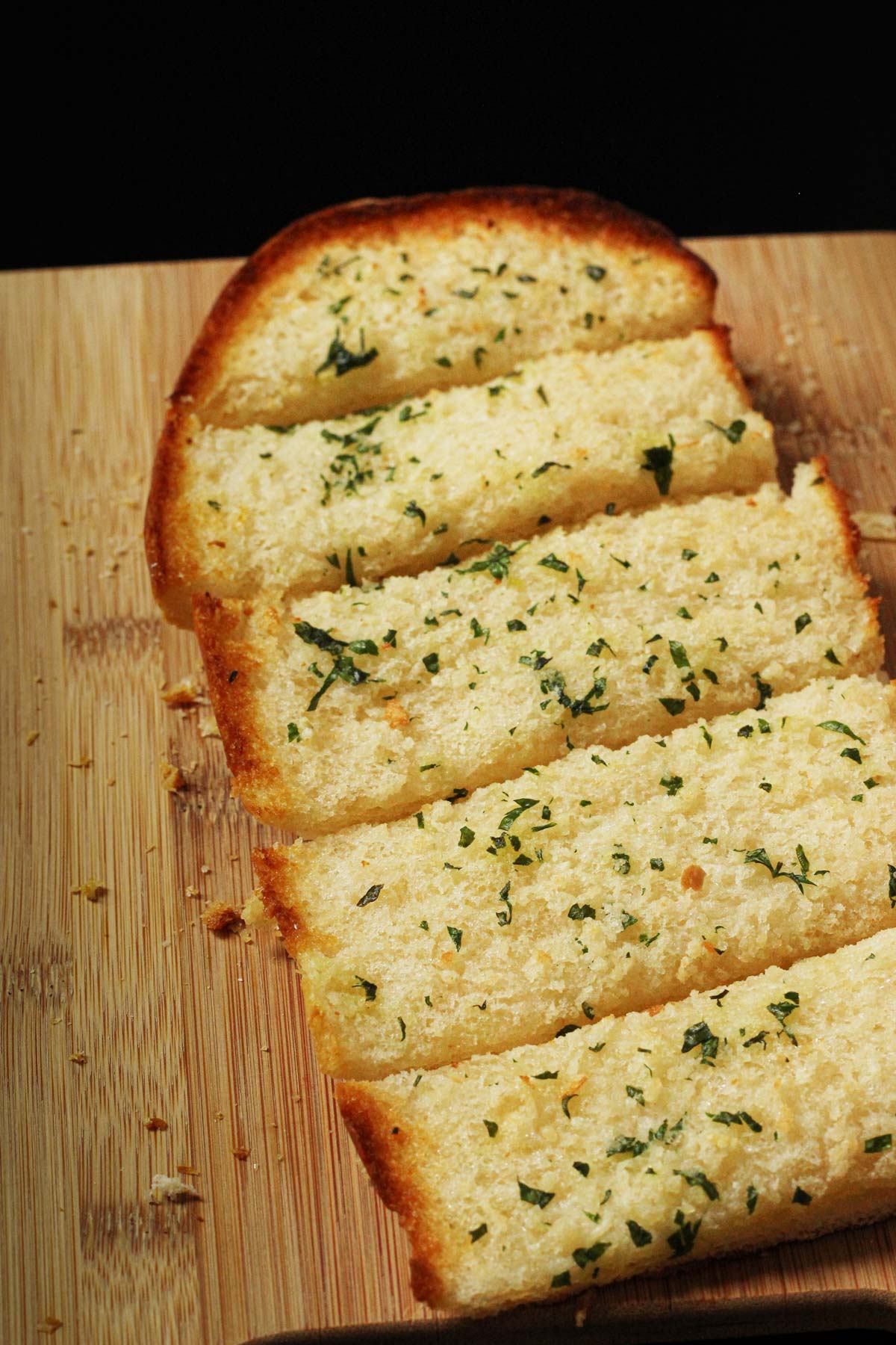 hunk of toasted frozen garlic bread sliced on a cutting board.