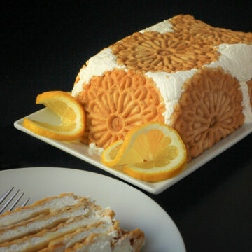 lemon ice box cake on white platter with lemon slices and a slice of cake on a dish.