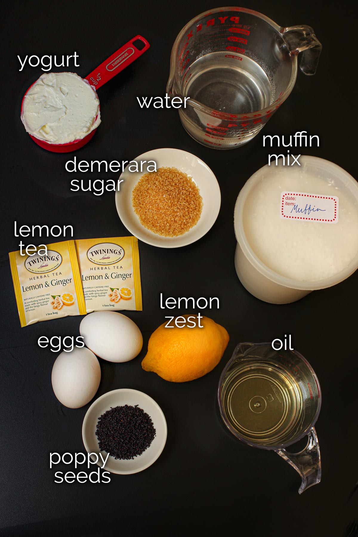 ingredients for lemon poppy seed muffins on black table top.