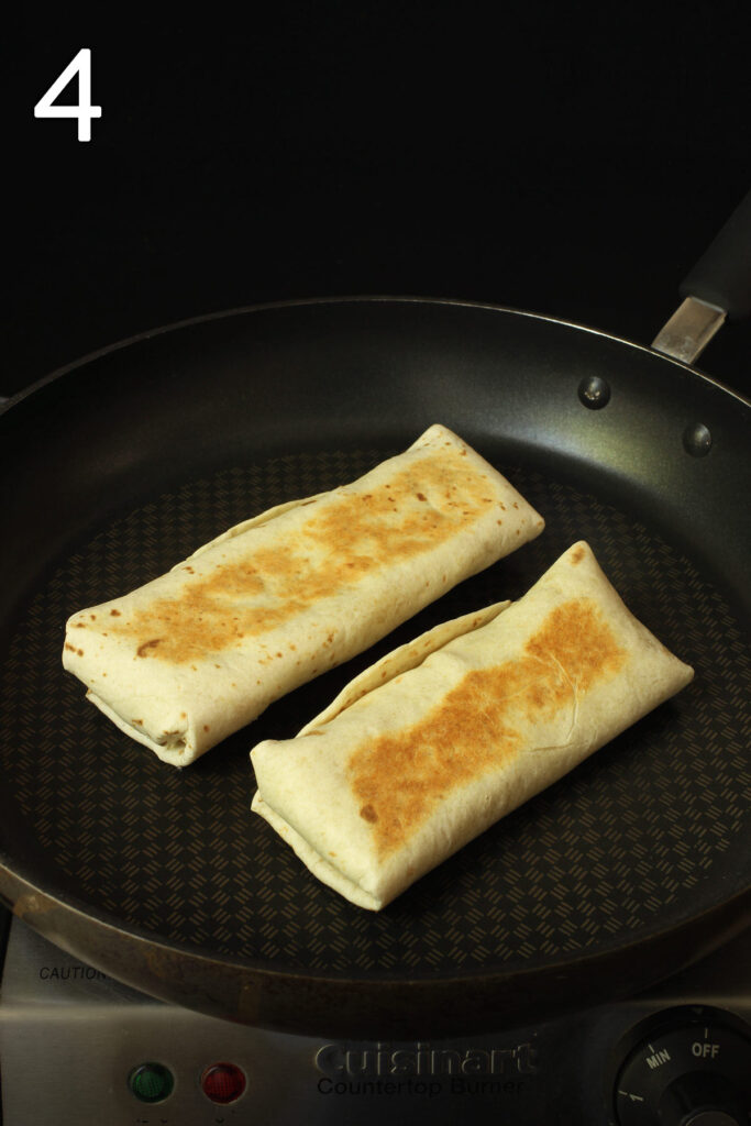 two burritos in a skillet browning and crisping.