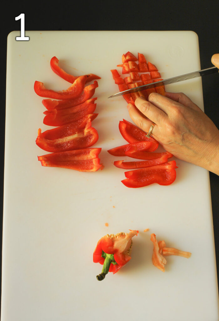 chopping red bell pepper on white cutting board.