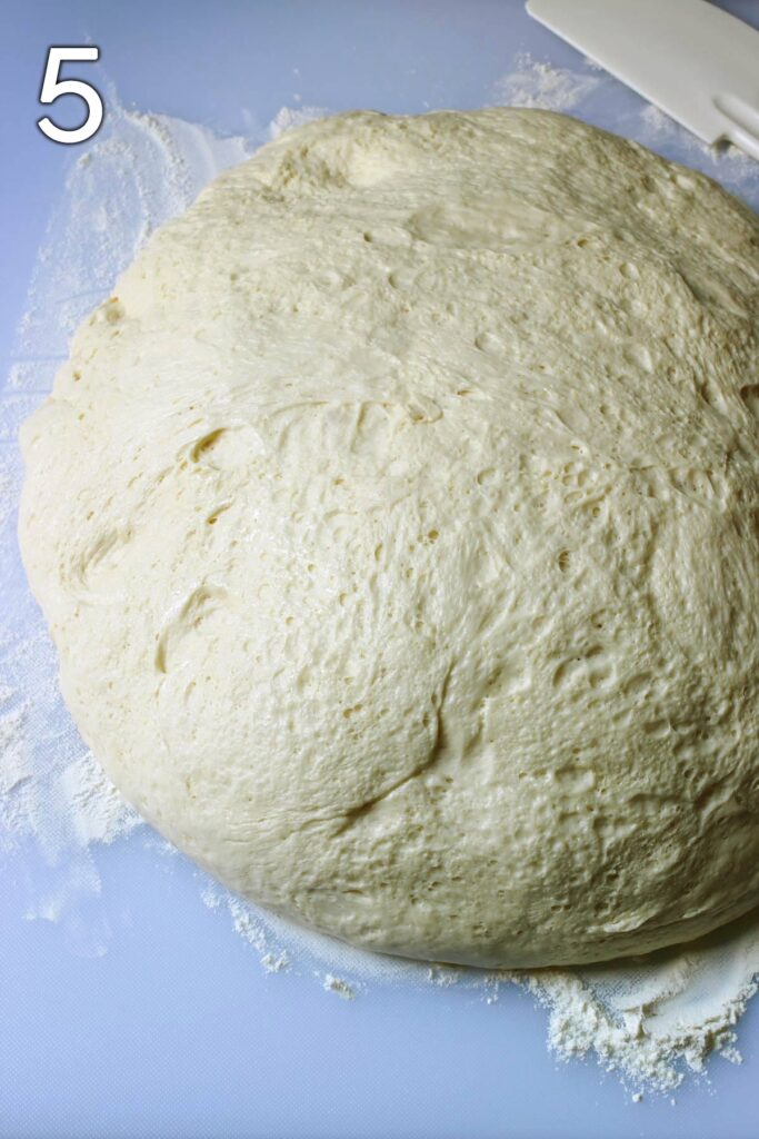 large risen dough ball on floured surface.