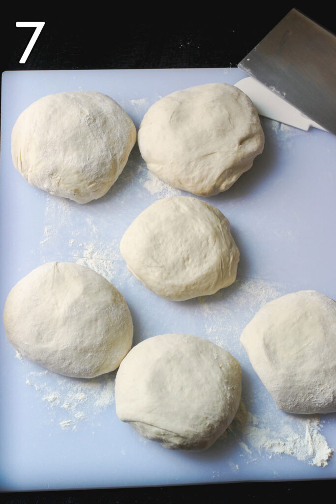 six small dough balls laid out on floured surface.