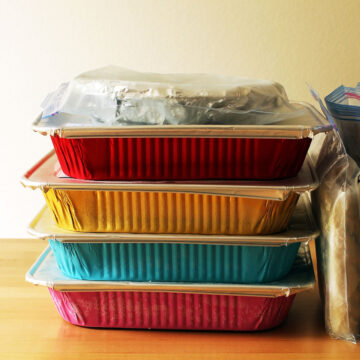 stacks of colored foil pans with freezer meals on counter.