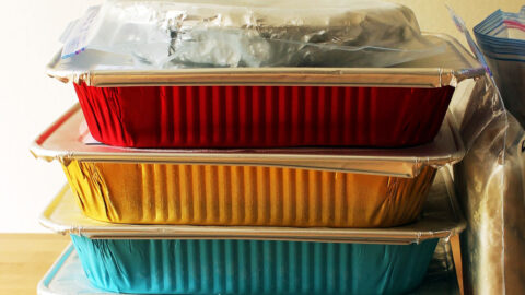 stacks of colored foil pans with freezer meals on counter.