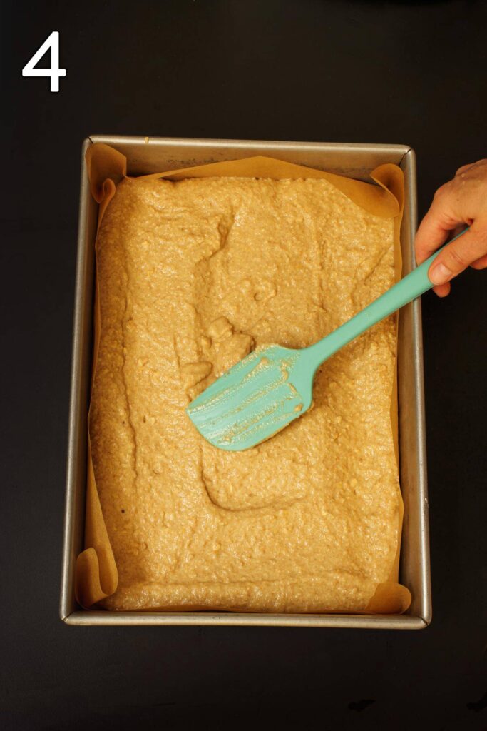spreading batter in prepared baking dish with a teal rubber spatula.