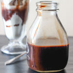 mocha syrup in a glass bottle next to an ice cream sundae.